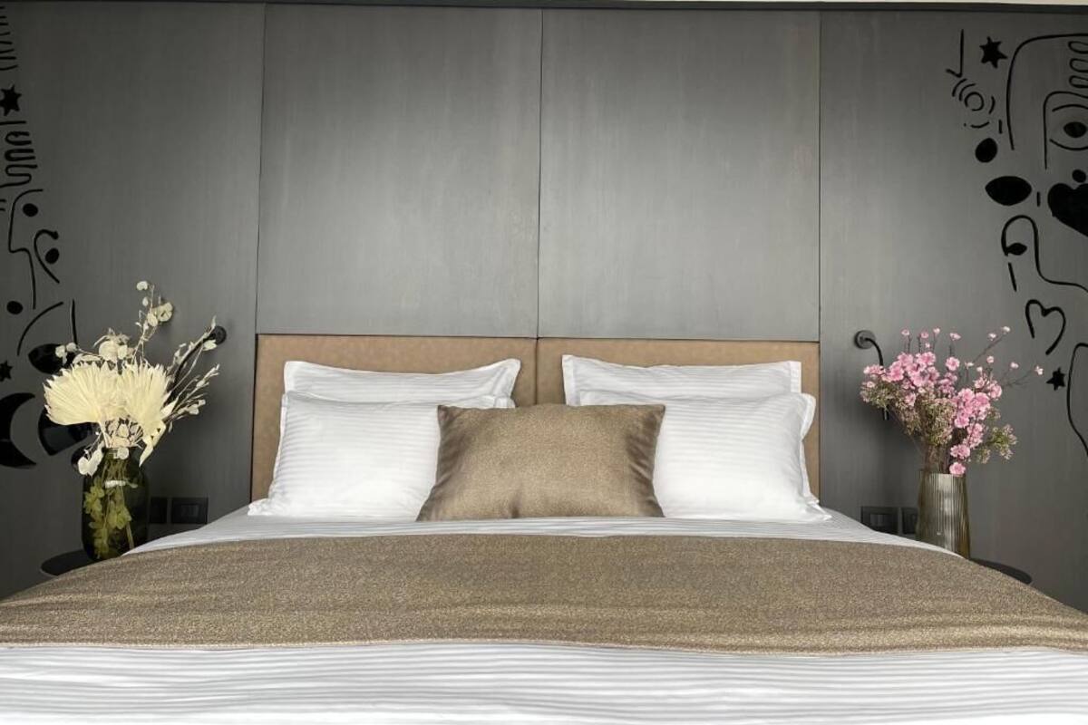Une chambre moderne avec un grand lit, deux tables de chevet et des œuvres d’art décoratives au mur.