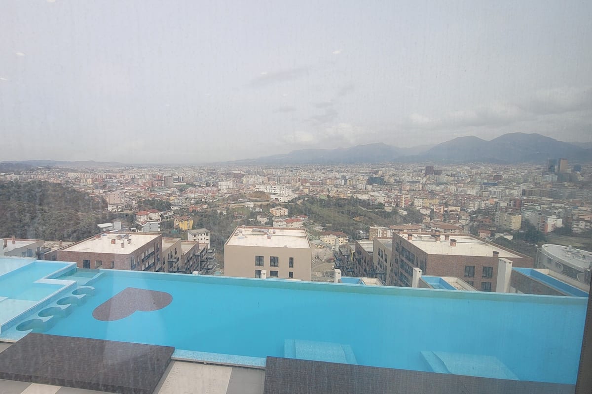 Une piscine sur le toit offrant une vue sur la ville et les montagnes en arrière-plan.