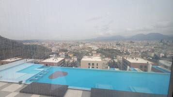 Piscina no terraço com vista para a paisagem urbana e montanhas ao fundo.