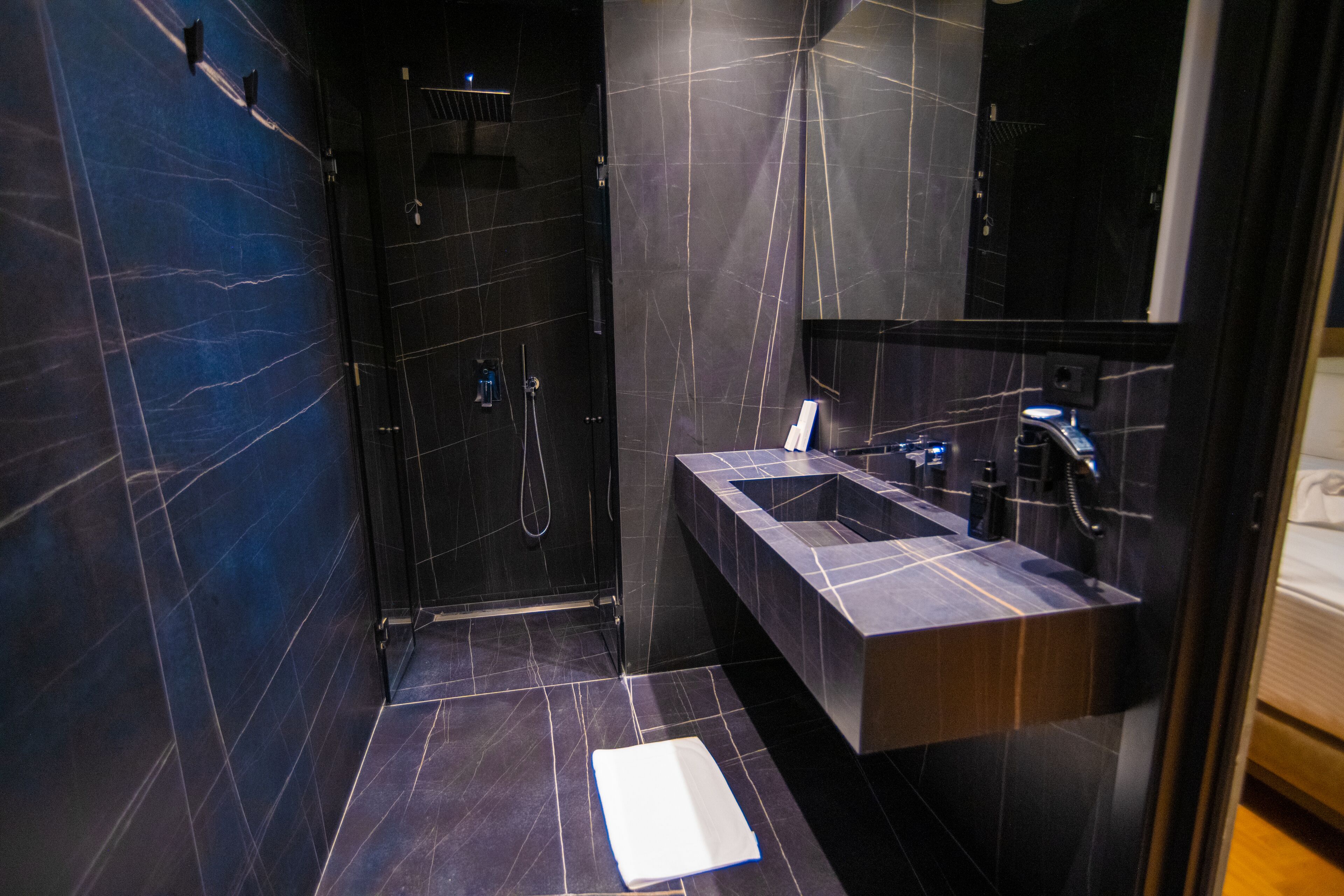 A modern bathroom with a glass-enclosed shower, a vanity with a sink, and a large mirror.