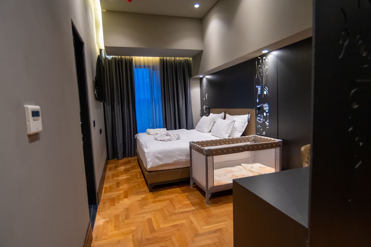 Une chambre d’hôtel moderne équipée d’un lit, d’un petit bureau, d’un miroir et d’une fenêtre avec des rideaux.