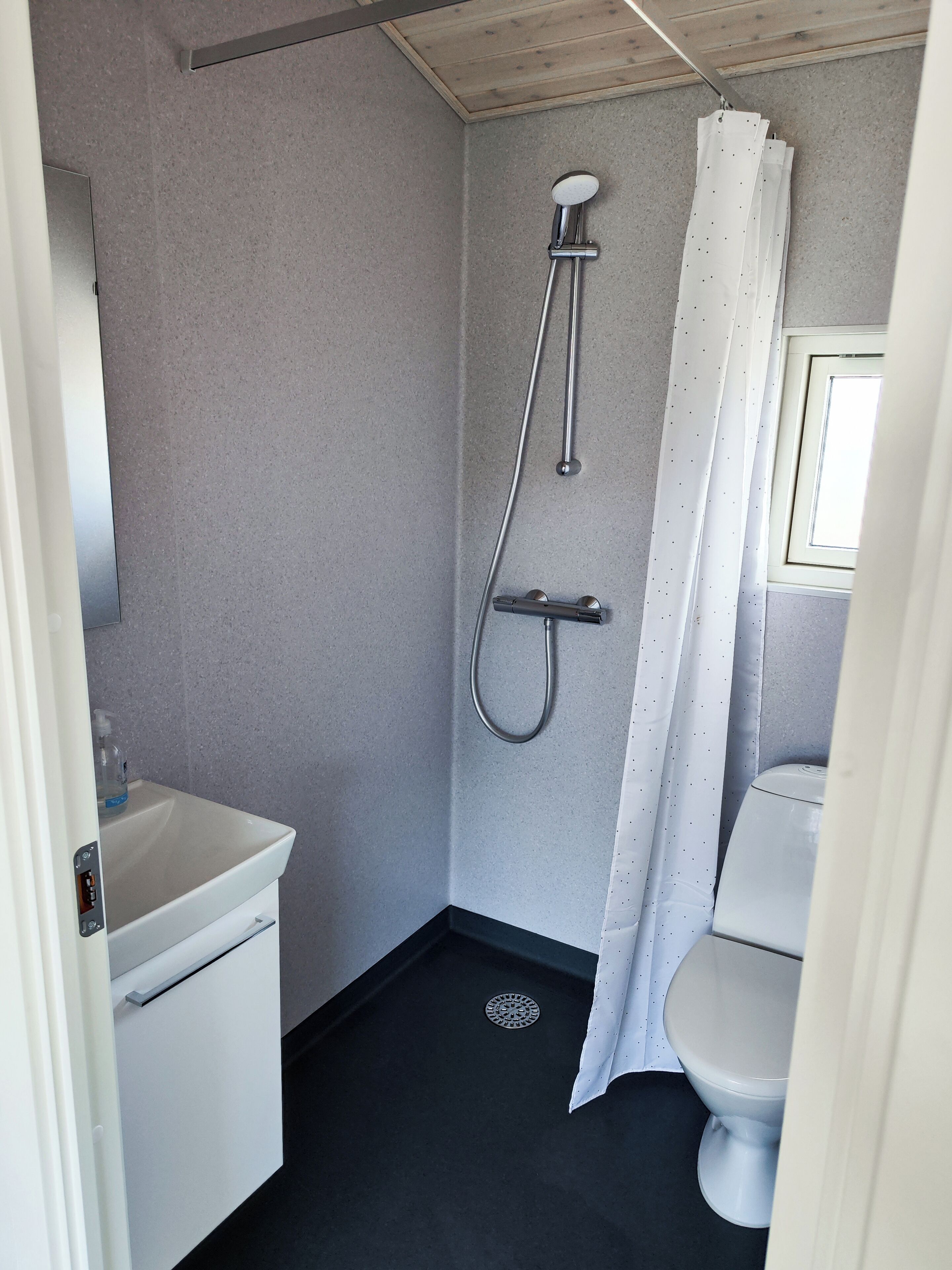 A small, modern bathroom with a shower, toilet, and sink.