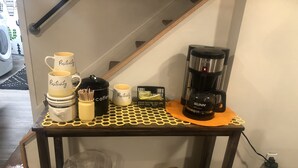 Una estación de café con varias cafeteras y tazas sobre una mesa de madera.