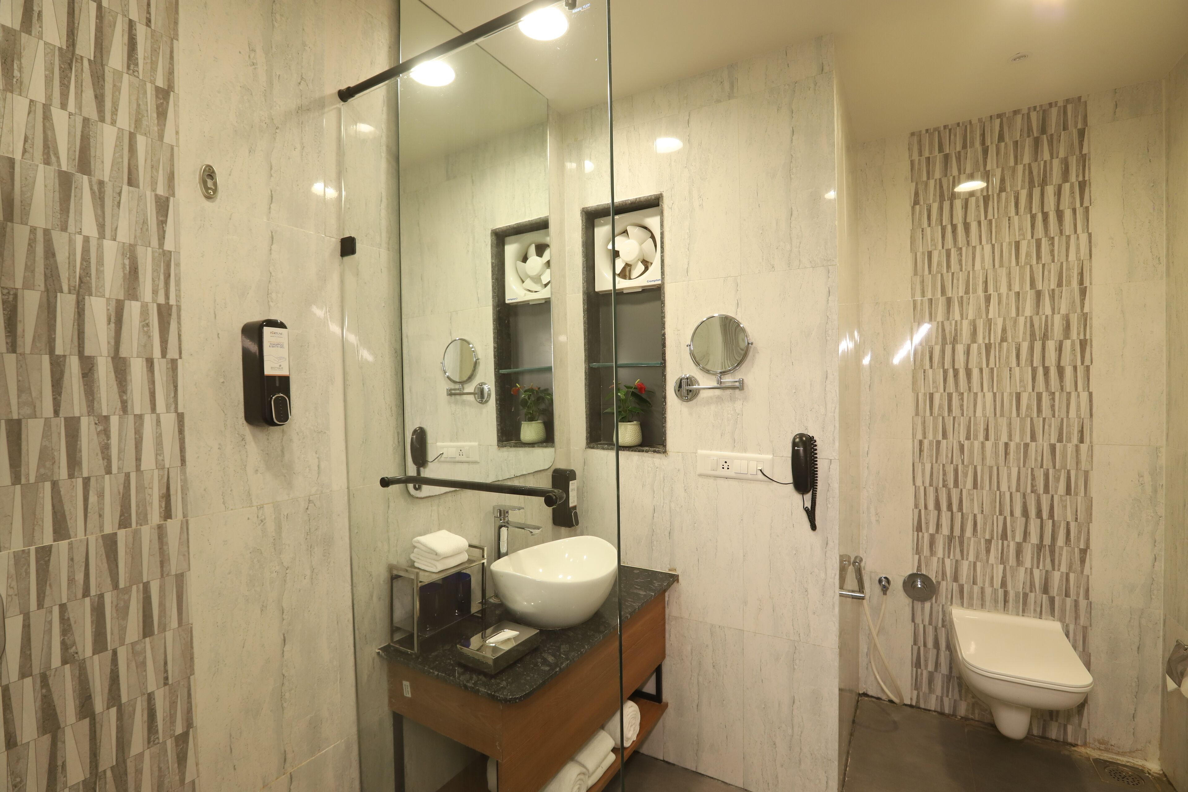 Une salle de bain moderne avec un grand miroir, un lavabo blanc et des toilettes.