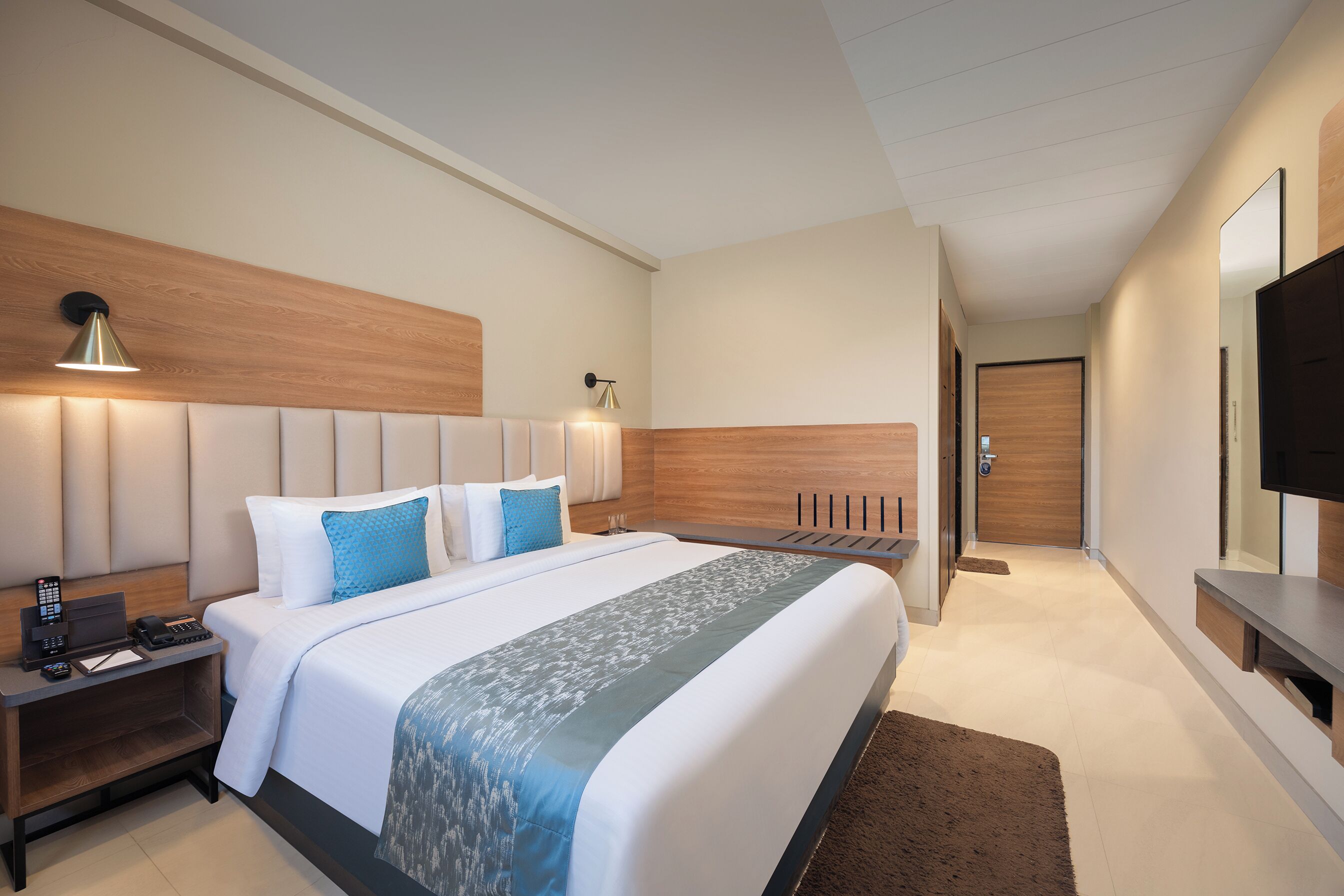 A modern hotel room with a large bed, bedside tables, a desk, and a flat-screen TV.