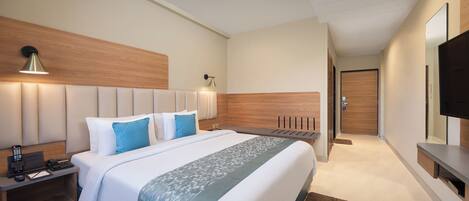 A modern hotel room with a large bed, bedside tables, a desk, and a flat-screen TV.