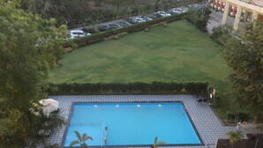 Piscina com deck revestido, rodeada por gramado e árvores.