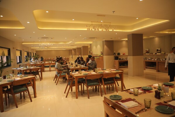 A spacious dining area with multiple tables and chairs, a central chandelier, and a modern interior design. - Fortune Statue Of Unity, Ekta Nagar - Member ITC Hotels' Group (Kevadia)