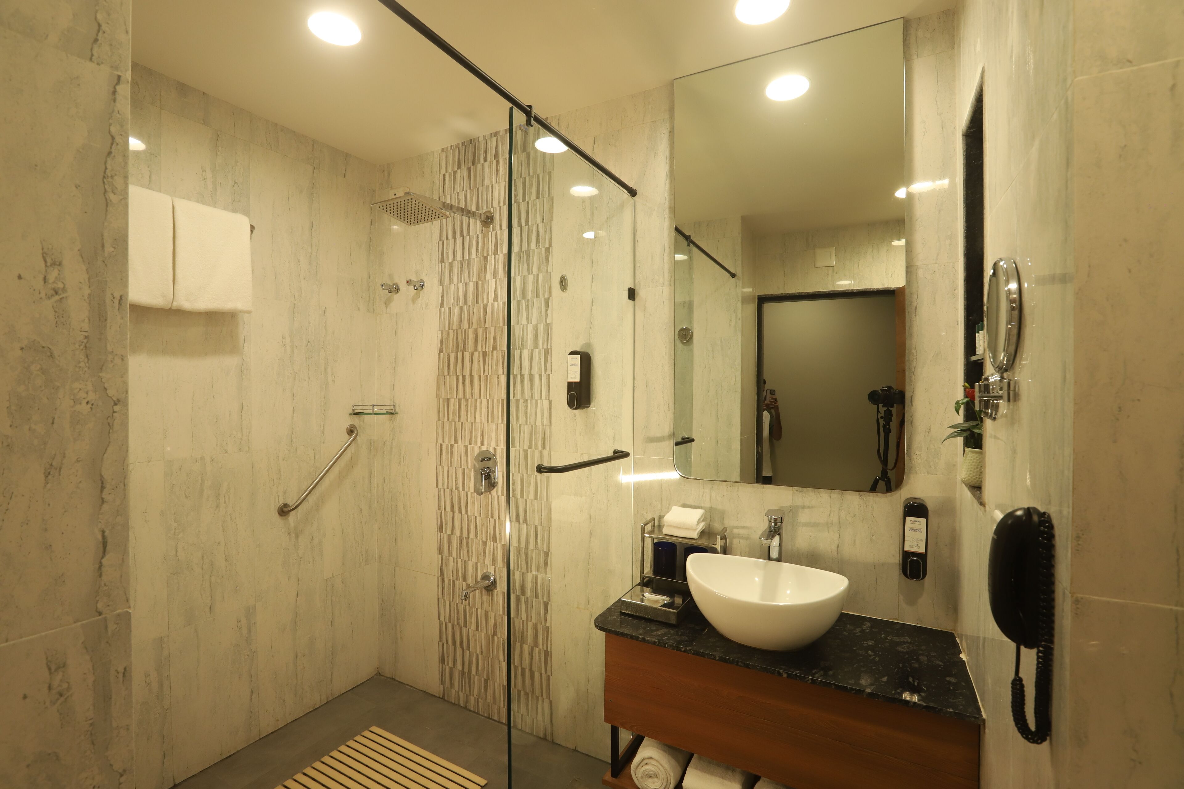Une salle de bain moderne avec une douche à parois de verre, un lavabo en marbre et un grand miroir.