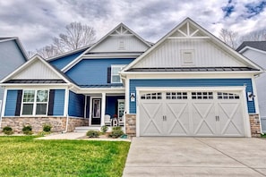 A two-story house with a garage, a front porch, and a stone foundation. - Coastal Club Resort House in Lewes: Coastal Elegance Awaits (Lewes)