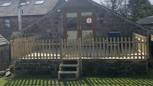 Un edificio de piedra con una terraza de madera y una puerta con un emblema circular.