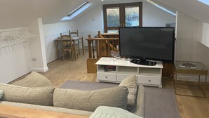 Un loft moderno con techos altos, tragaluces y un televisor de pantalla plana grande.