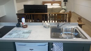 Cocina compacta con lavamanos, encimera y un pequeño comedor.
