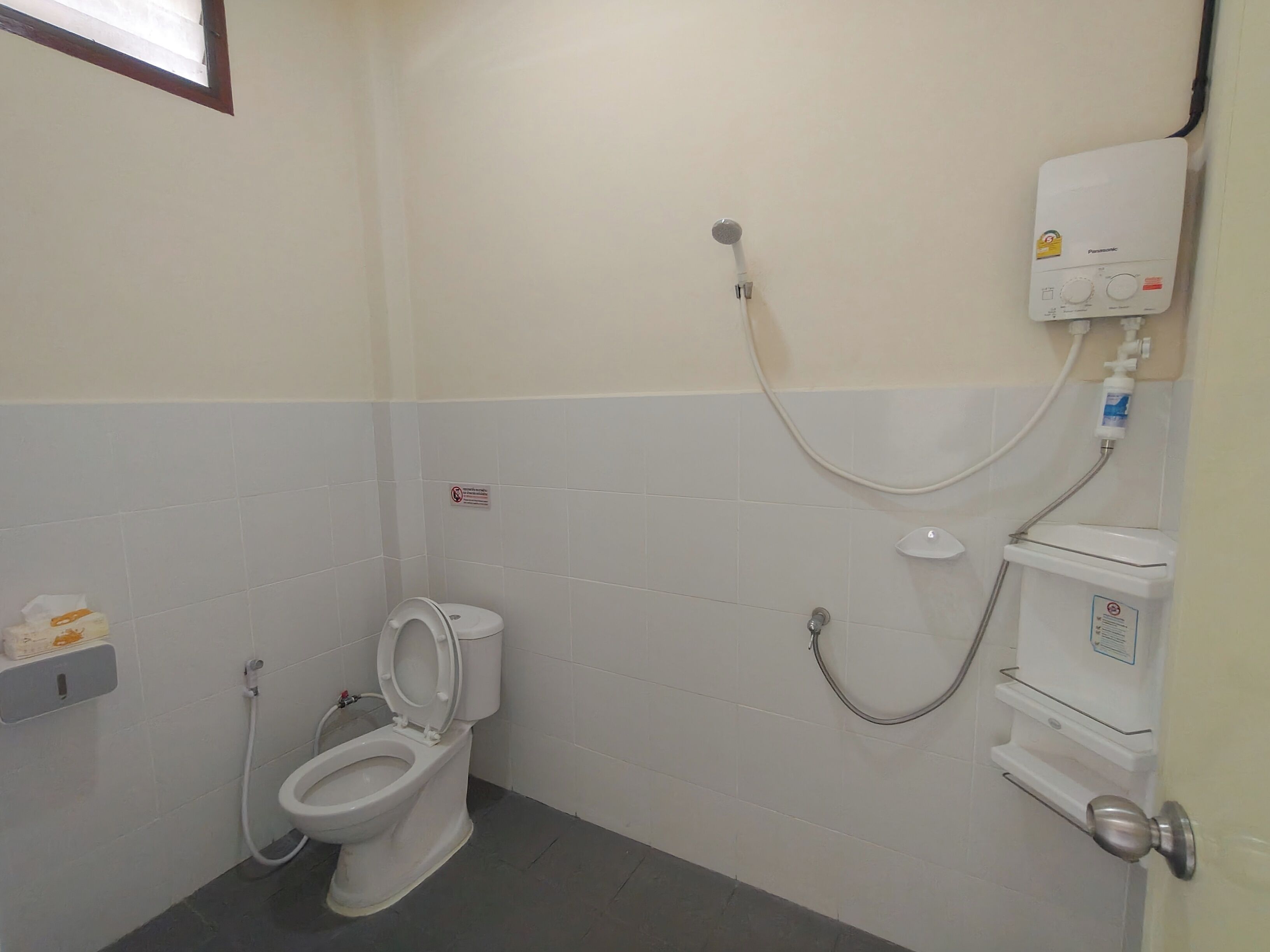 A small, clean bathroom with a toilet, a shower, and a toilet paper holder.
