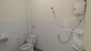 A small, clean bathroom with a toilet, a shower, and a toilet paper holder.
