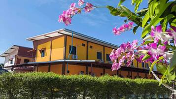 A yellow building with a flat roof and a covered walkway.