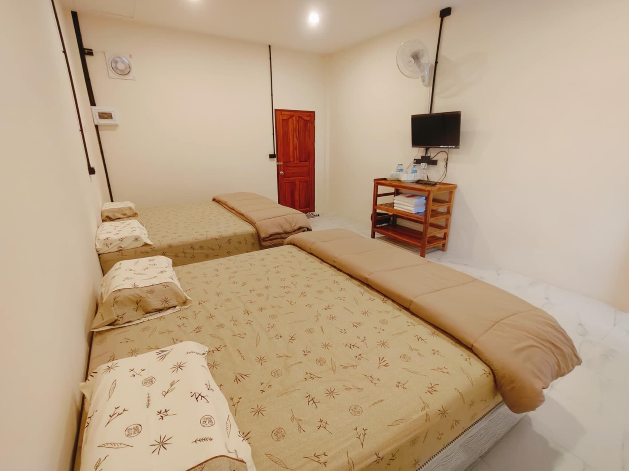 A room with two beds, a wooden nightstand, a TV, and a door.