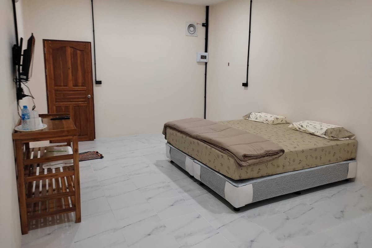 Ein Schlafzimmer mit einem Bett, einem Holztisch, einem Stuhl und einem Kleiderschrank.
