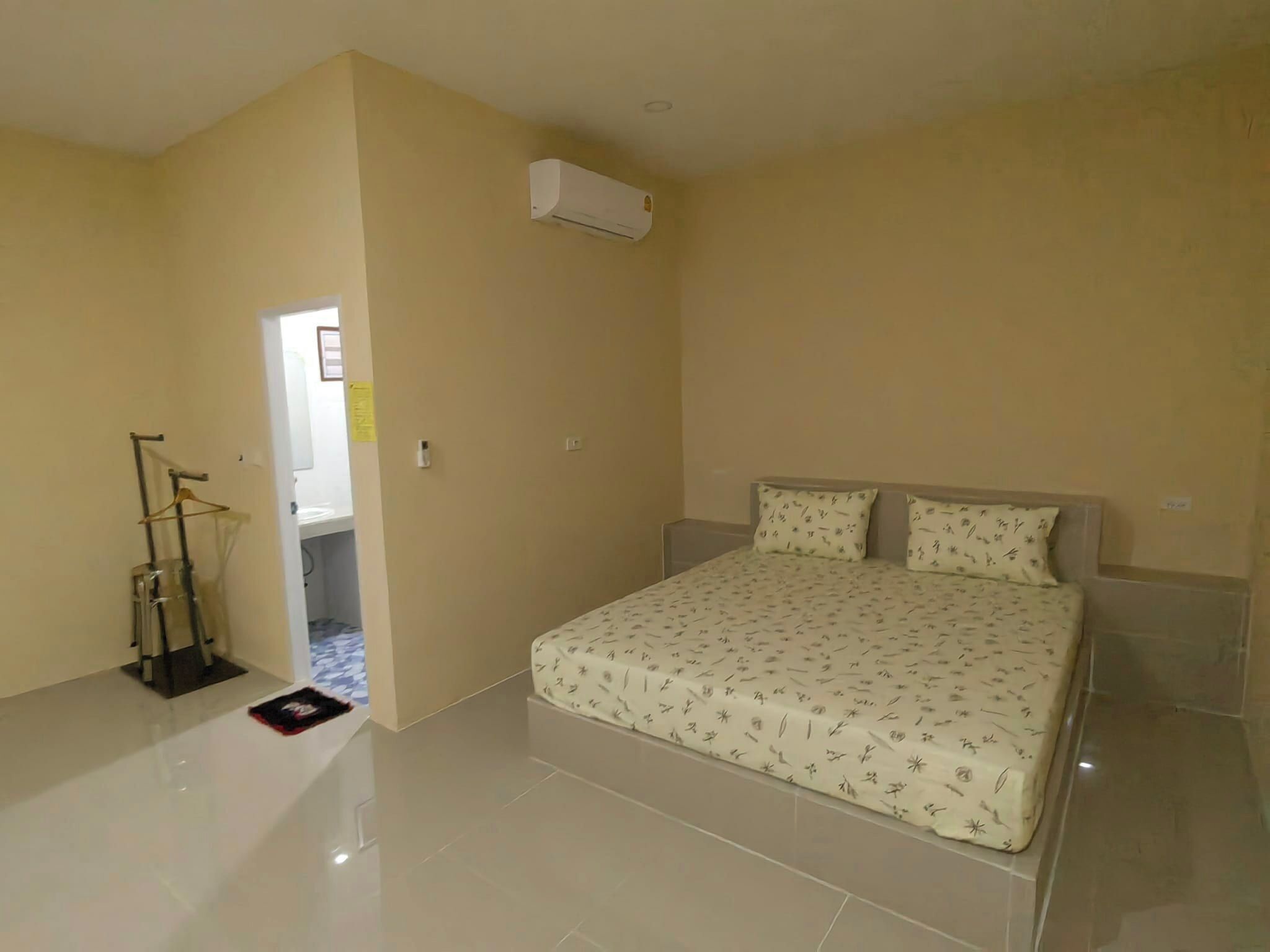 A bedroom with a bed, a hanging chair, and an air conditioning unit.