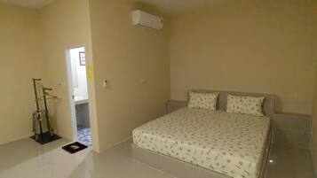 A bedroom with a bed, a hanging chair, and an air conditioning unit.