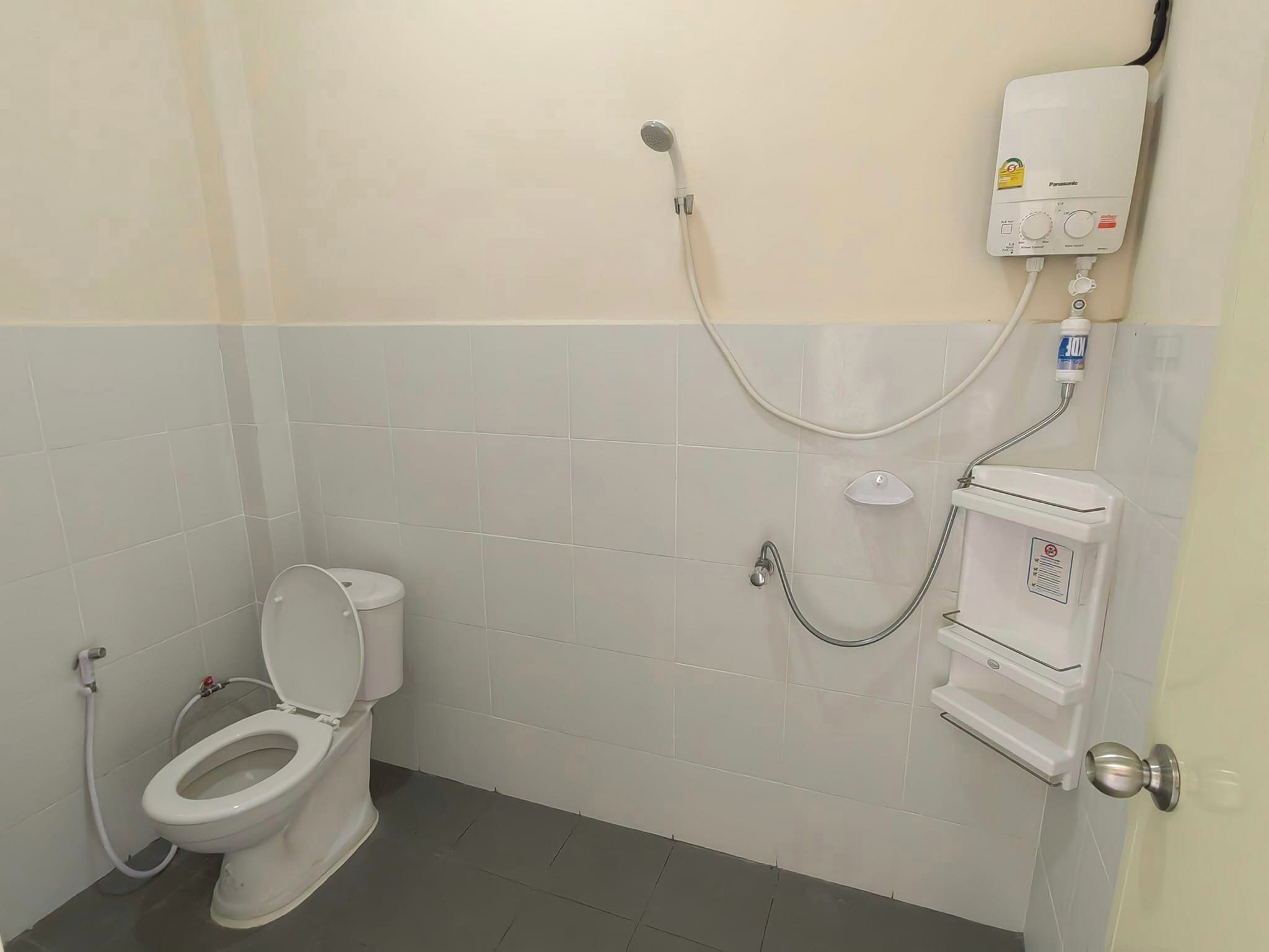 Un baño con inodoro, ducha y calentador de agua.