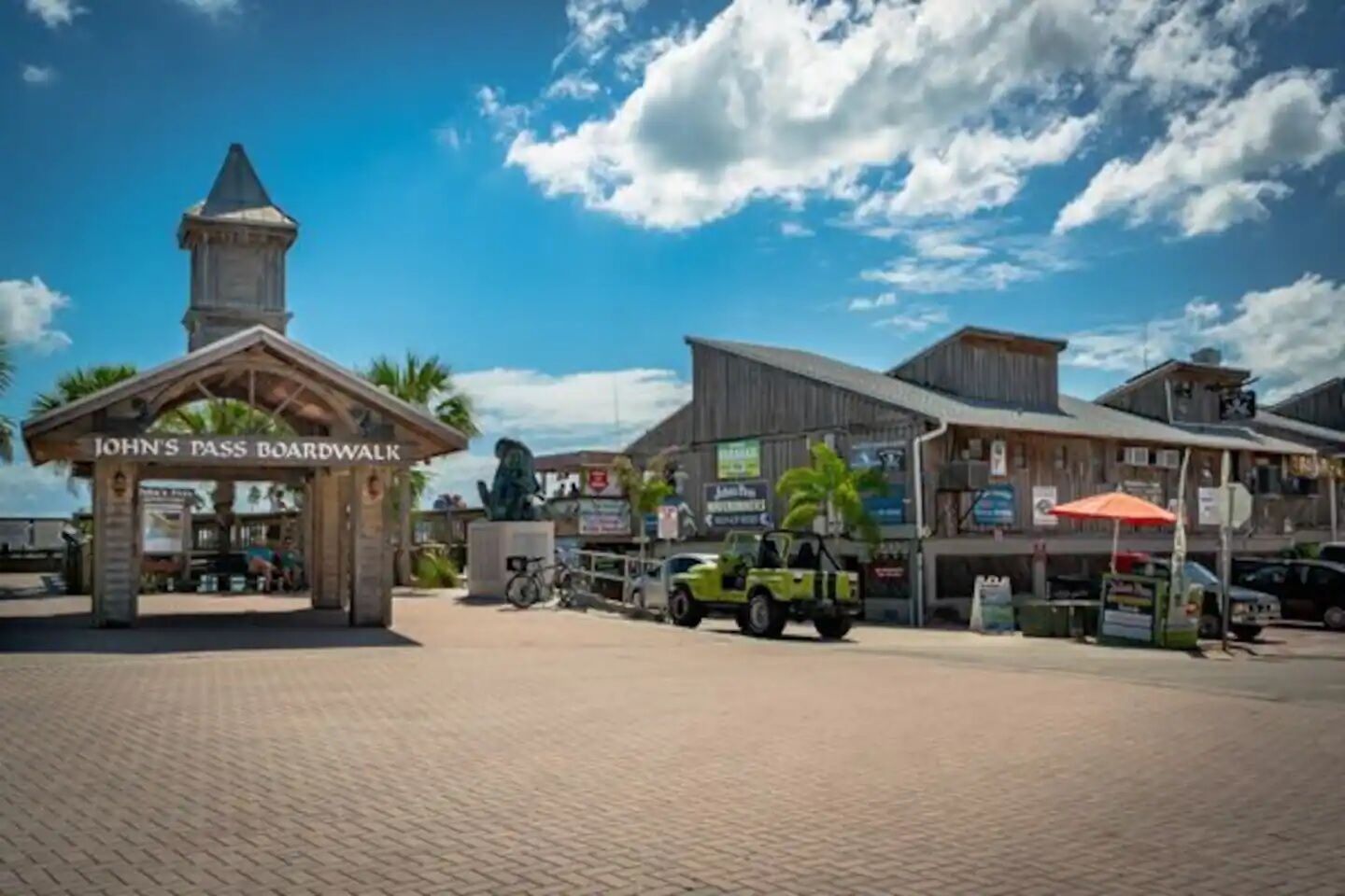 A building with a sign reading "John's Pass Boardwalk" and a statue in front.