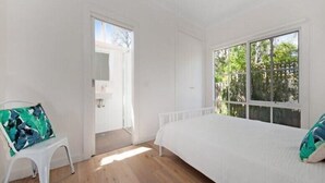 A bedroom with a large window, a bed, a white chair, and a door leading to a balcony. - Relaxed Sorrento Coastal Living (Sorrento)