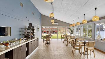 A modern kitchen with a dining area, large windows, and hanging wicker lights.