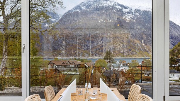 Una mesa de comedor con sillas, vista a la montaña y un lago.