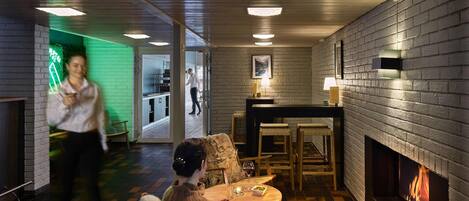 Una habitación acogedora con chimenea, zona de comedor y cocina a la vista a través de una puerta abierta.