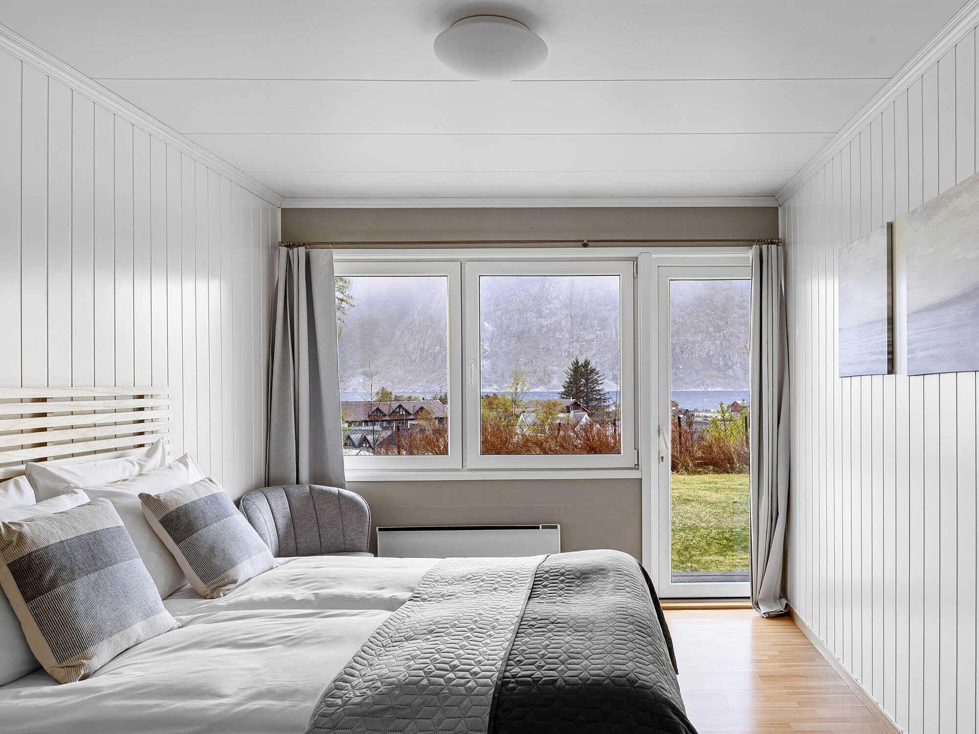 Ein Schlafzimmer mit Bett, Fenster und Blick auf eine Landschaft.