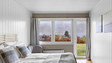 Un dormitorio con cama, ventana y vista a un paisaje.