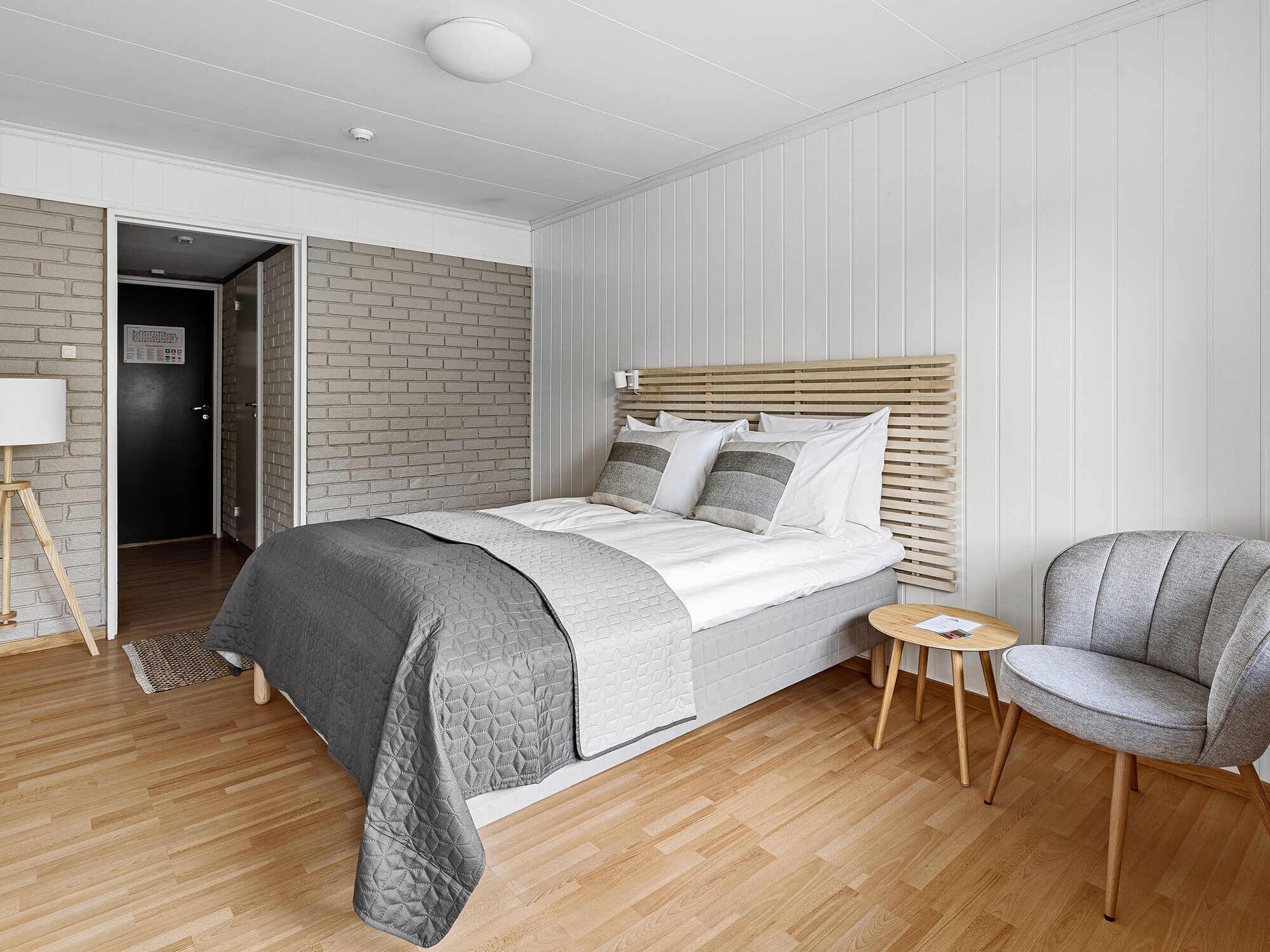 A modern bedroom with a bed, a chair, and a small table.