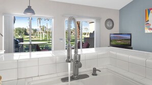 Una cocina moderna con un ventanal grande, un lavamanos integrado y un televisor de pantalla plana en la pared.