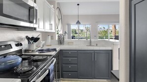 Una cocina moderna con estufa, microondas y grandes ventanales que ofrecen vistas al exterior.