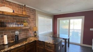 A kitchen with dark wood cabinets, a granite countertop, and a brick backsplash. - Cozy riverside cabin on the Neosho river (Chetopa)