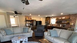 A spacious living room with a large round rug, two sofas, a coffee table, and a ceiling fan. - Cozy riverside cabin on the Neosho river (Chetopa)