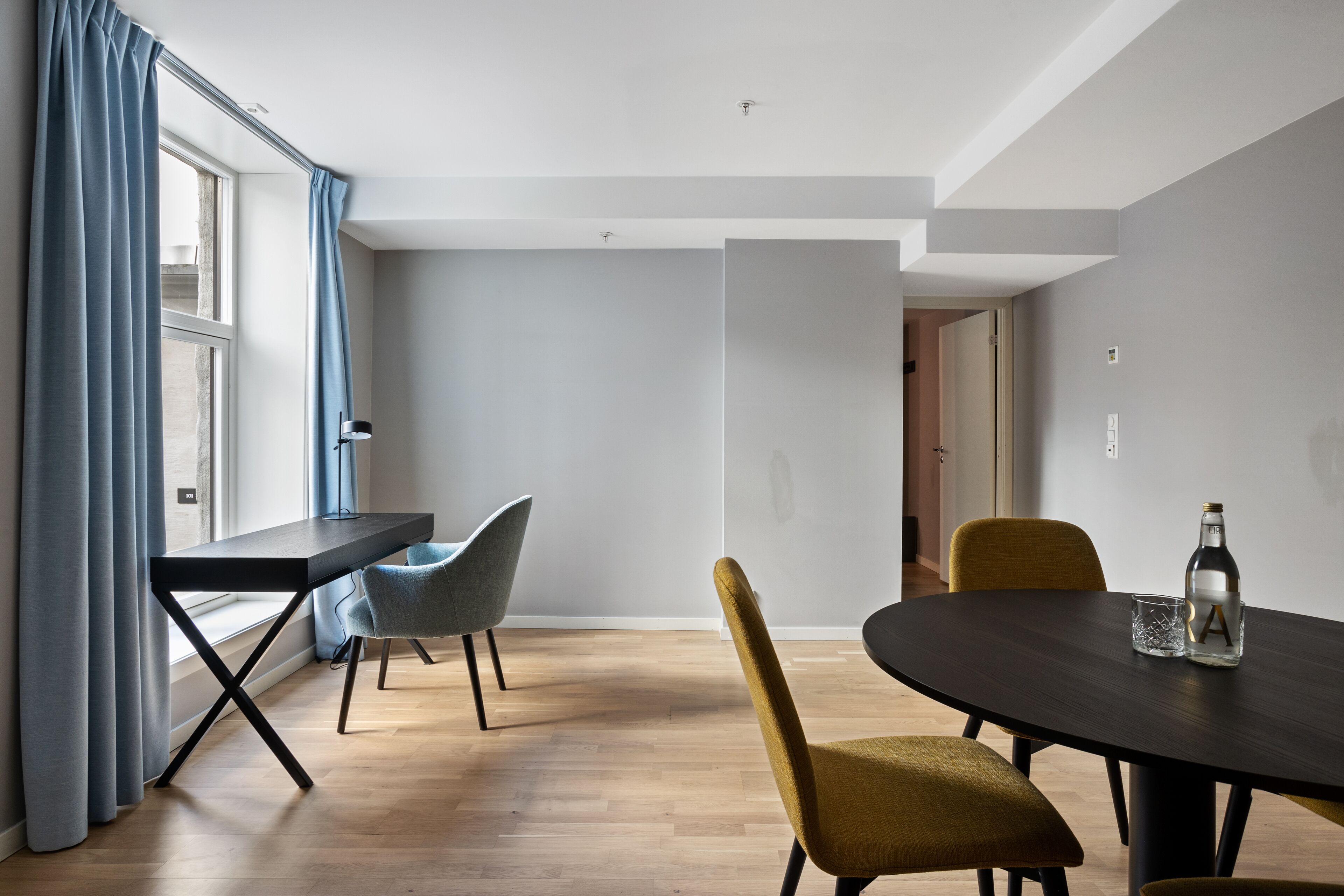 A modern dining area with a dark wooden table, two chairs, and a bottle of water.