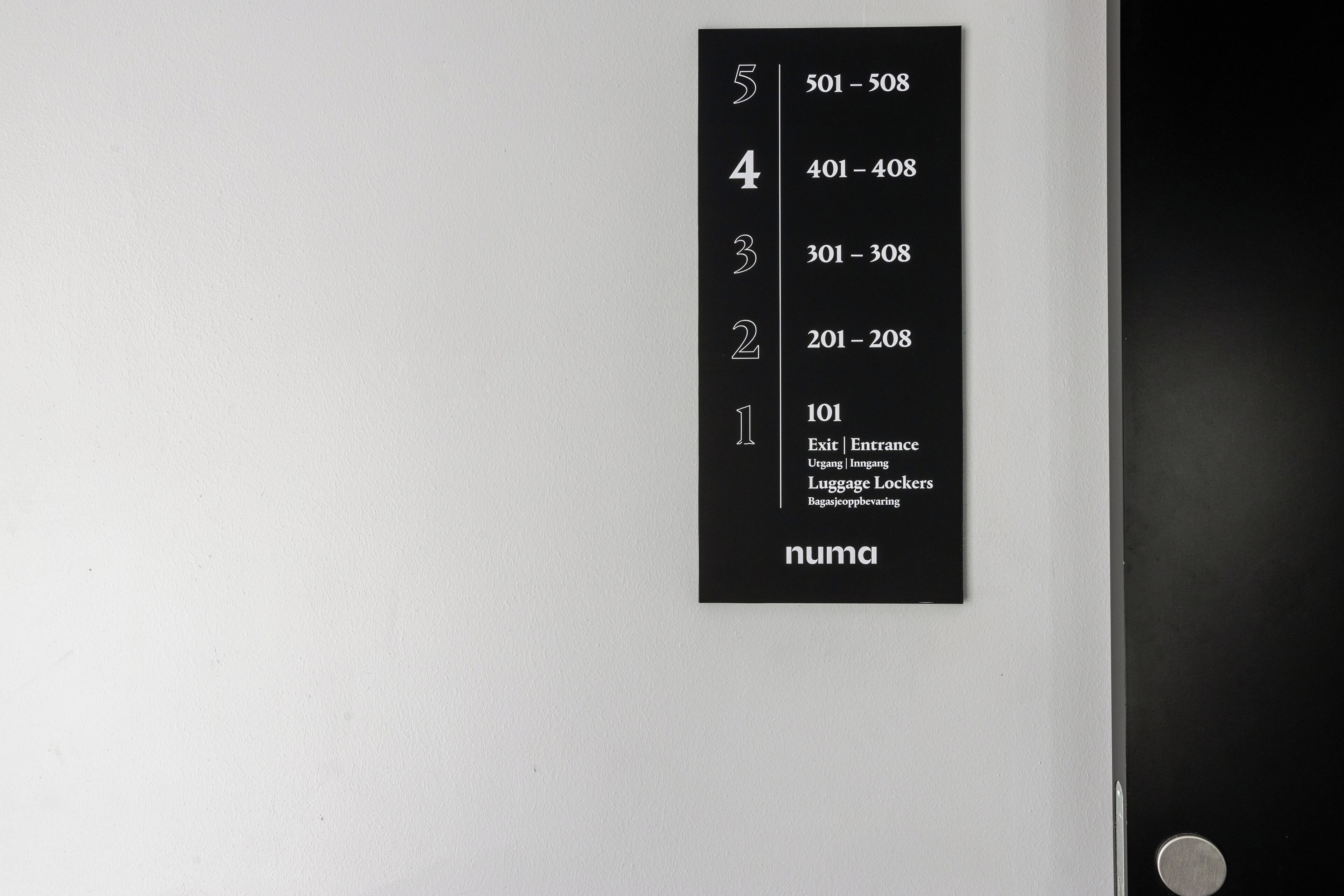A black sign with floor numbers and corresponding room ranges on a white wall.