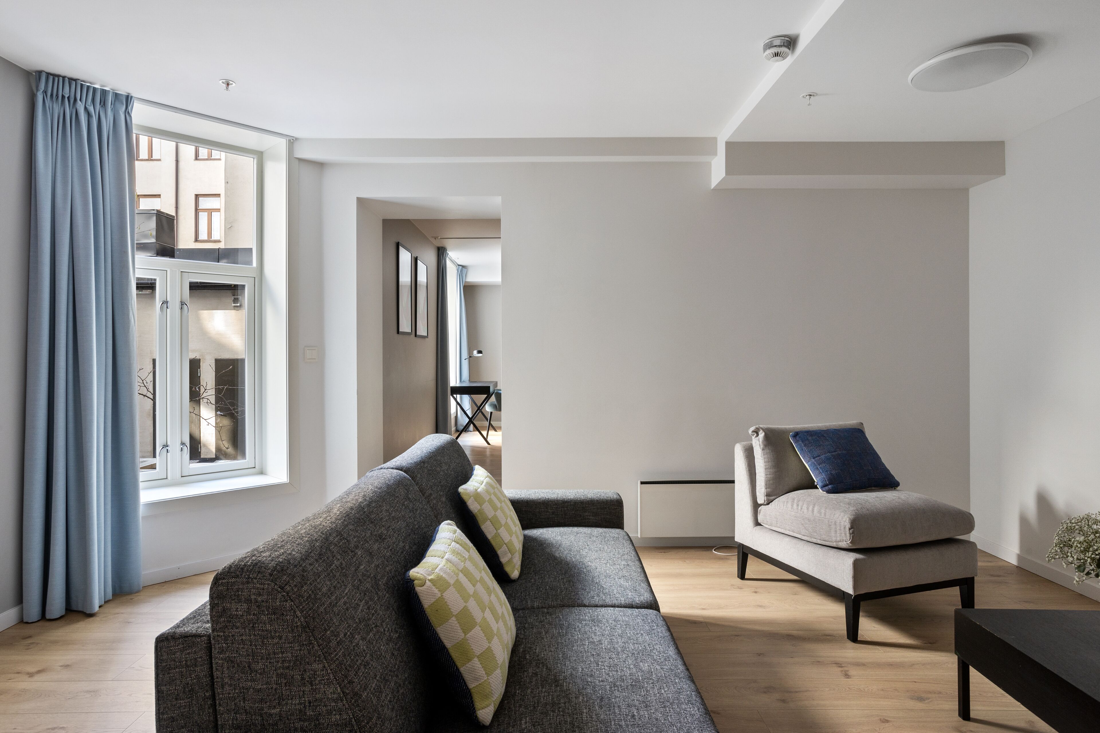 A modern living room with a grey sofa, a beige armchair, and a wooden floor.