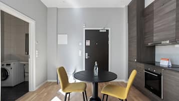 A modern kitchen with dark wood cabinets, a built-in oven, and a round black table with two yellow chairs.