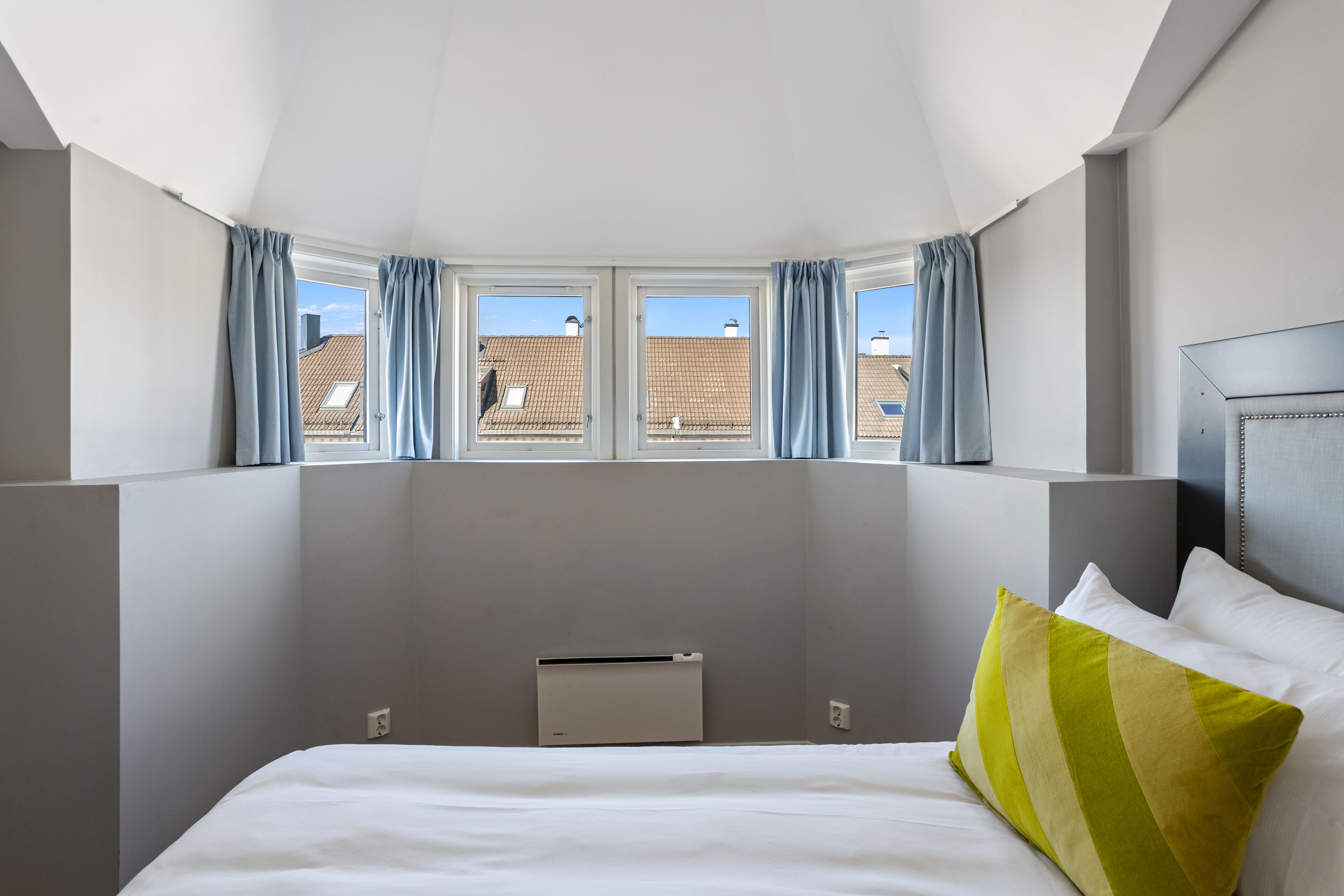 A hotel room with a large bed, a headboard, and a window with curtains.