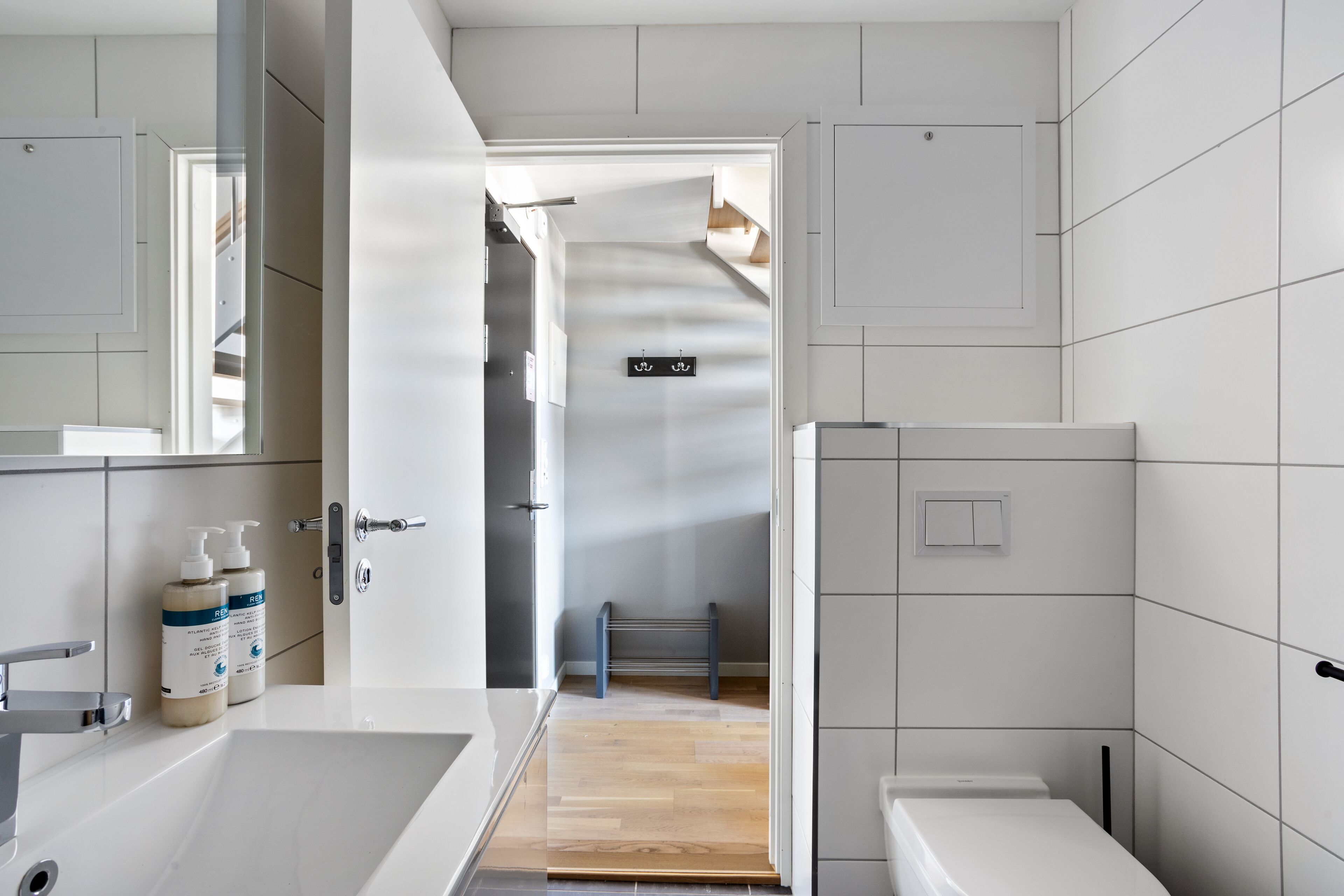 A modern bathroom with a bathtub, toilet, and sink. There are two bottles of hand soap on the sink counter.
