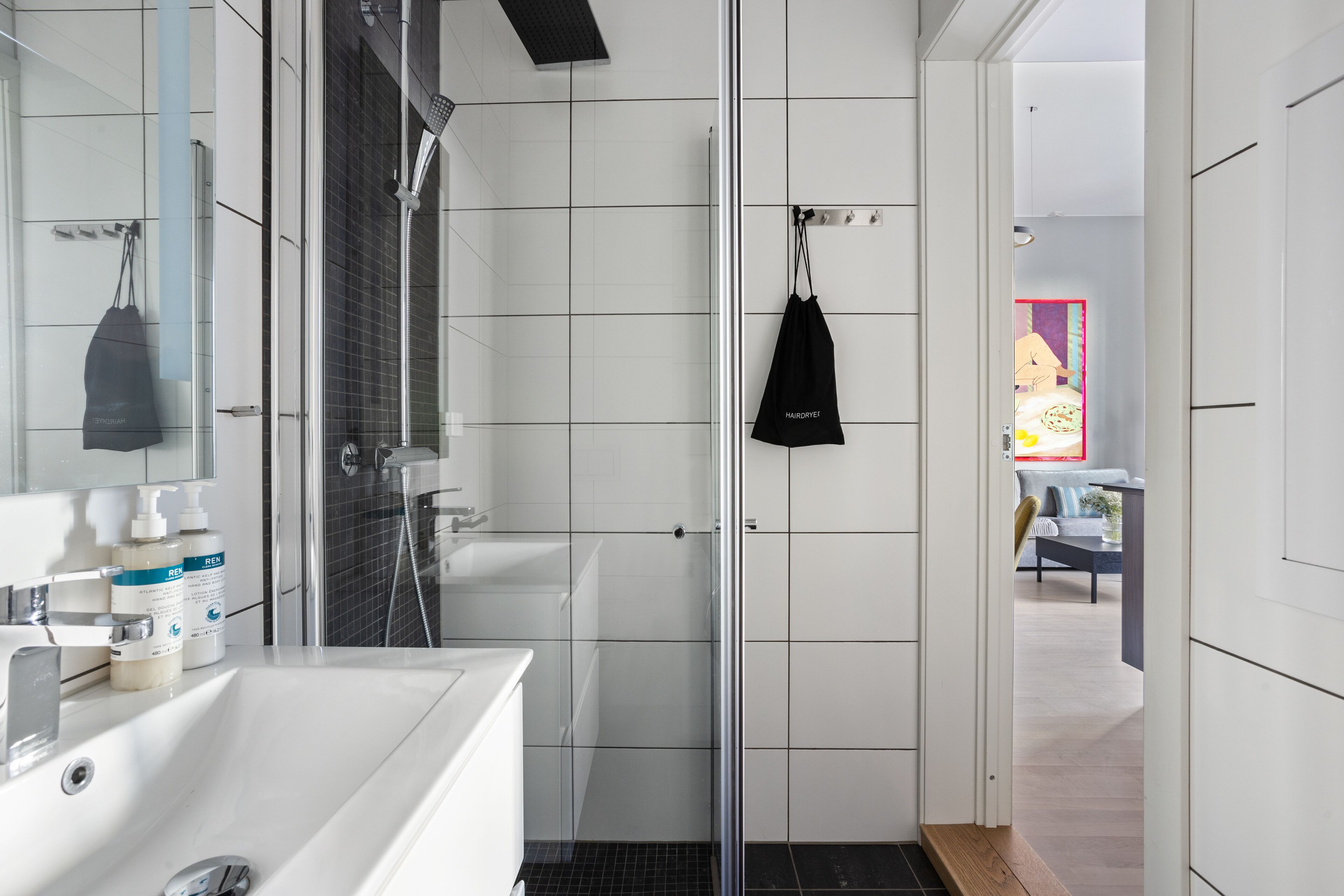 A modern bathroom with a white sink, mirror, and shower.