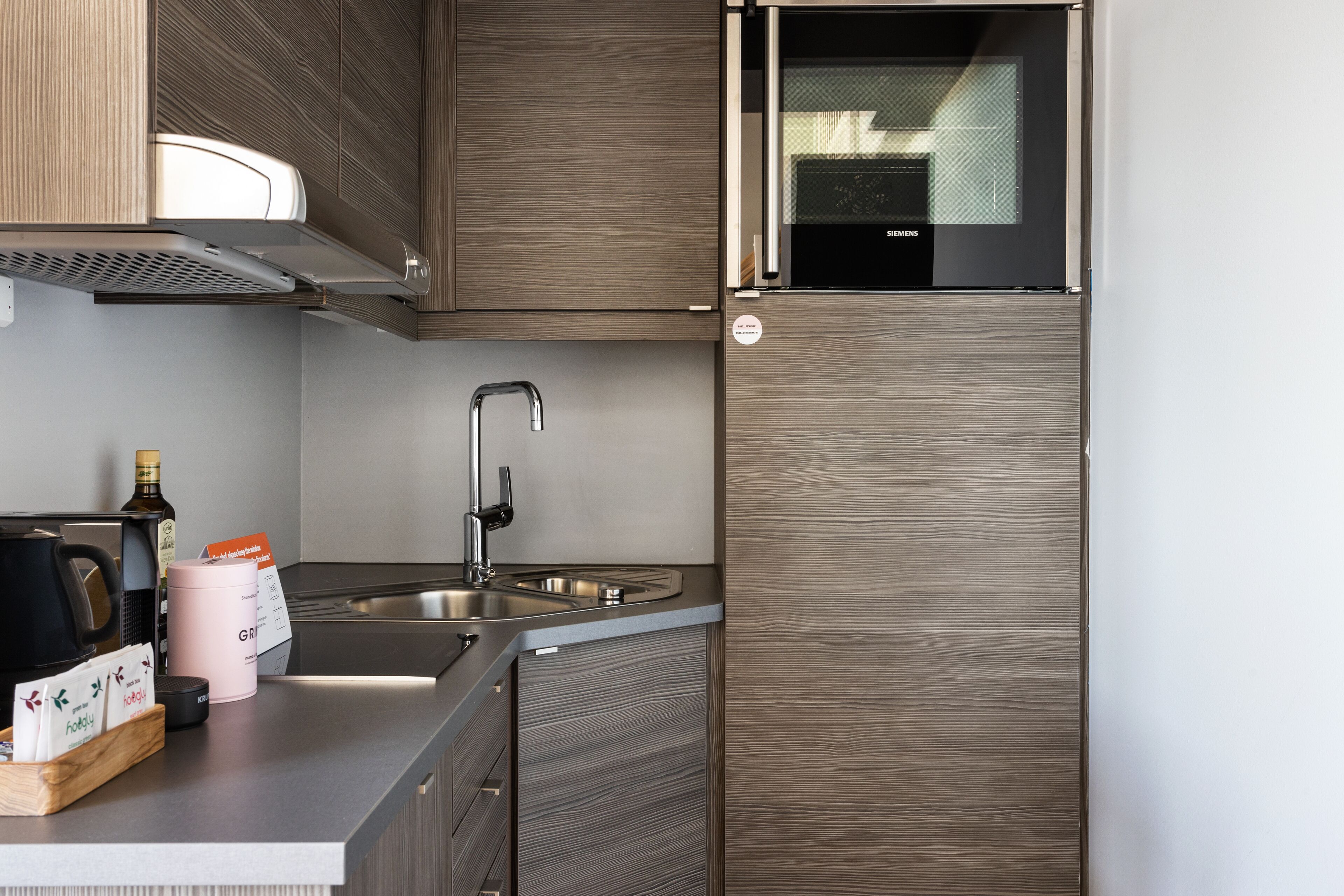 Una cocina moderna con horno empotrado, pileta de acero inoxidable y muebles de madera.