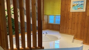 A wooden-paneled bathroom with a bathtub, a window with blinds, and a framed picture on the wall. - Le Clos Du Tulipier  (La Chapelle-du-Bard)