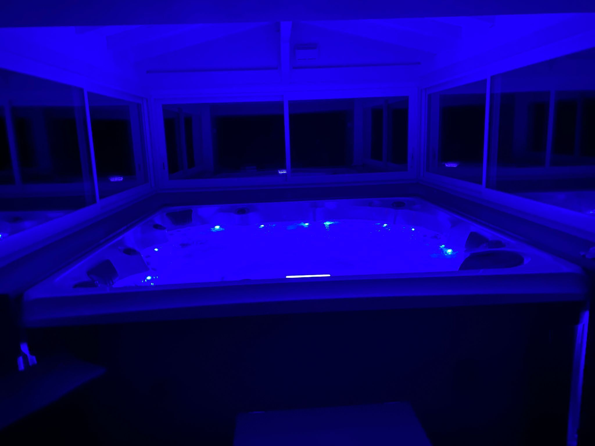 Una habitación con una bañera de hidromasaje grande y rectangular iluminada con luces azules.