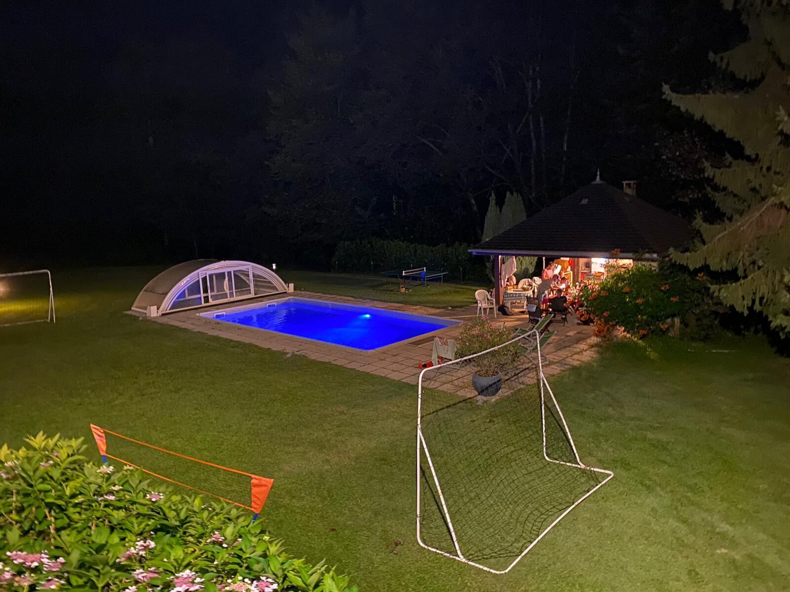 Una piscina con zona cubierta, un pabellón y un pequeño jardín con flores.