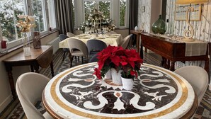 A dining area with a round table, chairs, and a Christmas tree. - Le Clos Du Tulipier  (La Chapelle-du-Bard)