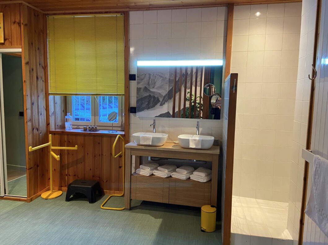 Une salle de bain avec des murs en bois, deux lavabos, un miroir et un porte-serviettes.